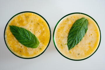 Two glasses of delicious lemonade orange smoothie from fresh oranges meant leaf view from above