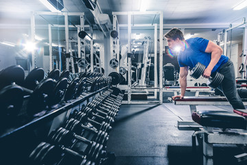 Fototapeta premium Sportsman lifting dumbbell on bench