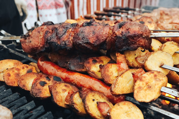 Meat baked on the grill with potatoes. Close up. Meat delicacies. Sausages homemade sausages on the grill. Street food. Homemade sausage.  Festival of street food and meat.