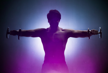 Obraz na płótnie Canvas Sportsman training shoulders in bright light