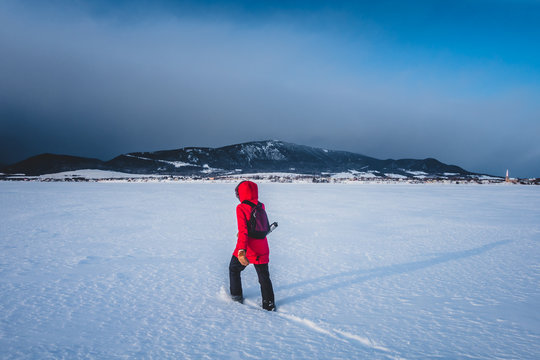 Woman Walking Lonely on a Frozen Lake during Cold Winter Day