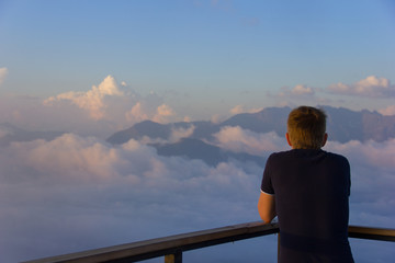 Fototapeta premium A man standing on a wooden platform at sunset high in the mountains of Sochi, Russia, 08/22/2017 