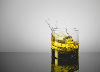 Splashing Glass of Single Malt Whisky over Gray Background