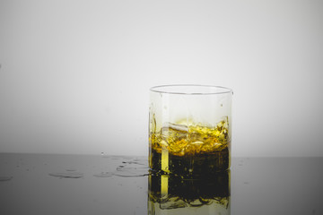 Splashing Glass of Single Malt Whisky over Gray Background