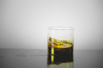 Splashing Glass of Single Malt Whisky over Gray Background
