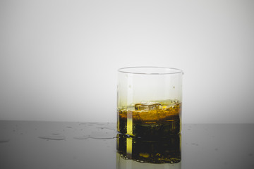 Splashing Glass of Single Malt Whisky over Gray Background
