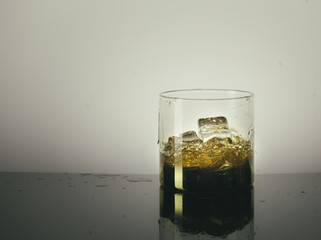 Splashing Glass of Single Malt Whisky over Gray Background