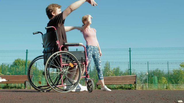 Disabled man plays basketball from his wheelchair With a woman, On open air, Make an effort when playing