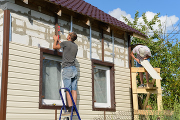 August 6, 2017: two workers polish the apartment building with vinyl siding. Moskakassy. Chuvashy....