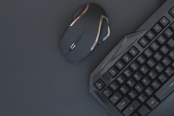 Black mouse, keyboard isolated on a dark background, top view. Flat lay gamer background. Workspace with a keyboard and mouse on a black background. Copyspace