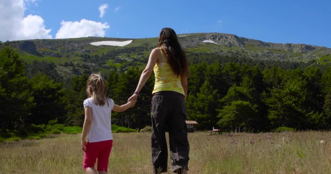 Little girl and woman holding hand, walking together in meadow and they separate in opposite directions, in the countryside of Guadarrama mountains, near Madrid, Spain, Europe. 4k video. 
