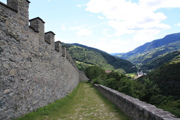 Wanderweg entlang einer mittelalterlichen Burgmauer mit Zinnen