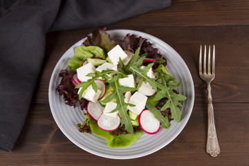 vegetarian salad in a plate on a wooden table, dark, top view