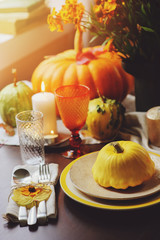 Fototapeta na wymiar autumn traditional table setting for Thanksgiving or Halloween, with candles squash and pumpkins.