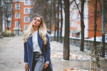 street style portrait of young woman walking in city in autumn or winter in warm coat