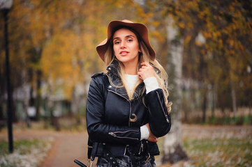 Fototapeta na wymiar fashion autumn portrait of young happy woman walking outdoor in fall park in hat and leather jacket