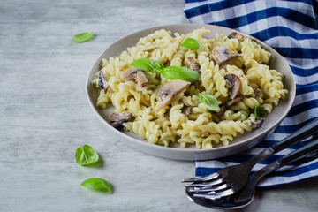 Pasta Fusili with mushrooms, sause cream and basil on stone concrete table. Italian Food Concept. Top view, copy space