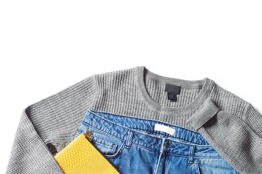 Flat lay fashion photo/ Women's clothes in casual style. Gray woolen sweater, blue jeans and yellow clutch. Autumn and winter clothes