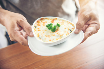 hand Chef suggesting exquisite restaurant appetizer Spinach with cheese in white bowl