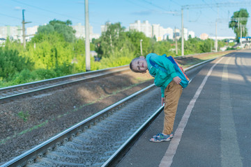 Fototapeta na wymiar A little boy with a backpack is waiting for the train. A child stands alone on the platform in anticipation of an electric train.