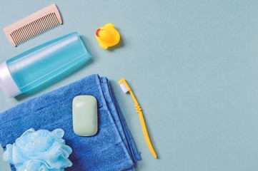 Flat lay photo toiletries set, personal care items/ Wooden hair brush, shower gel or shampoo for men, cotton towel, sponge, soap bar, rubber duck and yellow toothbrush