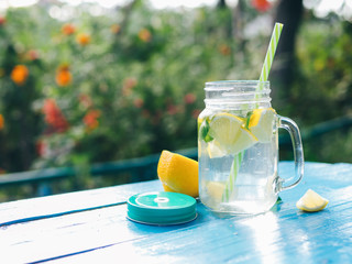 Lemonade in a glass jar with slices of lemon and mint on a wooden table