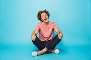Fototapeta na wymiar Portrait of a cheerful young curly haired man showing