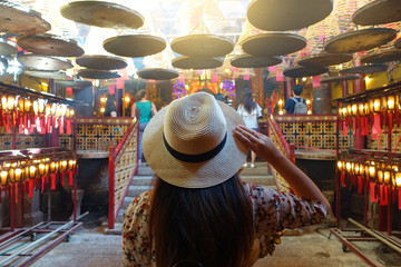 Tourist is visiting and looking beatiful  joss stick released smork decoration inside Man Mo  Chinese buddhistTemple in Hong Kong.   - obrazy, fototapety, plakaty