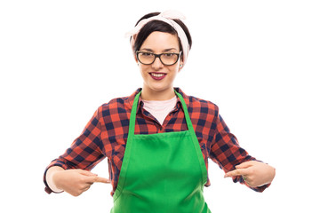 Young pretty pin-up girl pointing fingers to green apron .