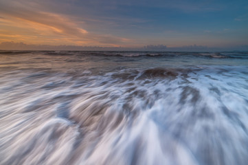 sunset seascape with waves trails. soft focus due to slow shutter and water movement.