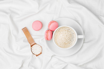 Cup of coffee and macaroons on bed. Flat lay, top view