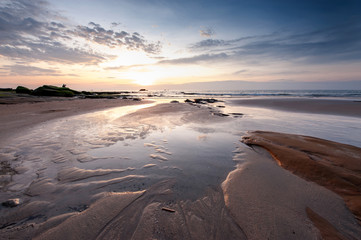 beautiful sunset at the beach. bright sun and beautiful cloud formation. slow shutter effect.