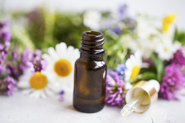 Obraz na płótnie Canvas Flowers and plants essential oil bottle with dropper, closeup of essential oil bottle
