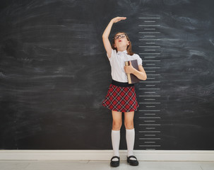 Kid measures growth on background of blackboard