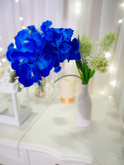 Blue orchid artificial flowers decorate on white table