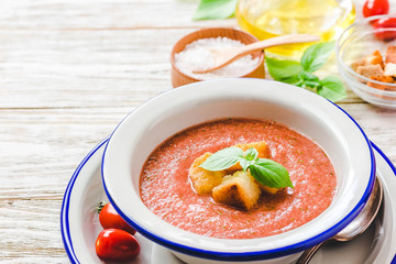 Healthy summer cold tomato soup, gazpacho with basil and garlic bread. Selective focus, space for text.