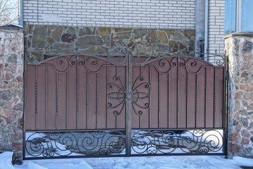 brown metal gate on a fence in the street in the snow