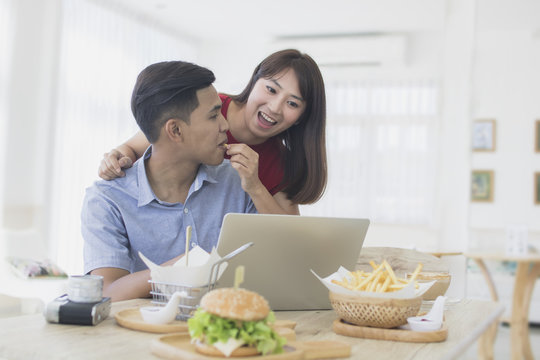 Asian couple lifestyle use laptop and eat breakfast at home