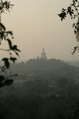 Temple on a wooded hillside seen at dusk through smoggy skies