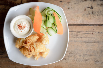 Top view of fried squid on a white plate on wooden