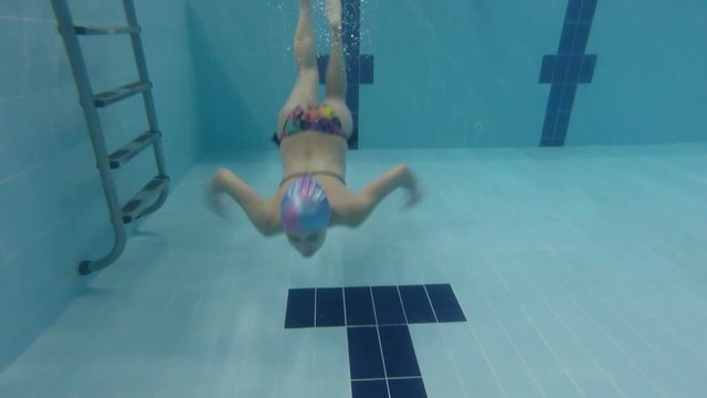 Sporty pregnant girl swimming underwater in the pool. The view under water.