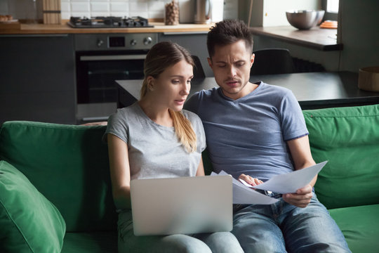Worried couple confused reading bad news in bank loan documents or money debt calculating high domestic bills or rent payment checking papers with laptop, family discussing financial problems concept