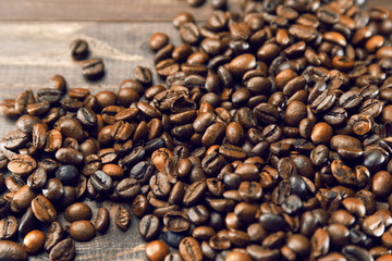 Grains of coffee scattered on a wooden brown background
