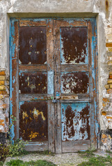 Old architectural details - rusty door in an ancient building locked with small rusty padlock