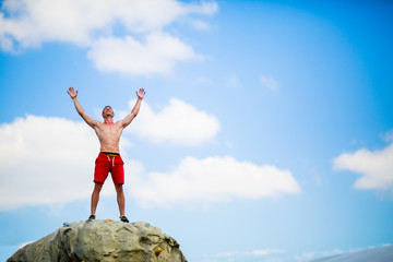 Photo of happy man climber on top of stone against blue sky