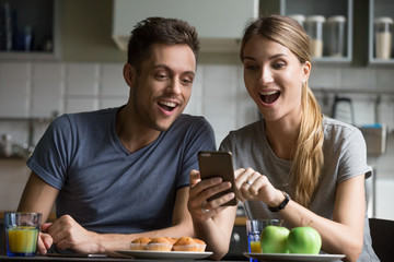 Excited young couple surprised by unbelievable good news, fantastic online travel offer looking at...