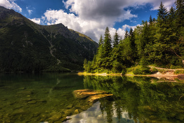 Fototapeta na wymiar Beautiful alpine lake in the mountains, summer landscape with blue cloudy sky and reflection in crystal clear water, natural background, Morske Oko (Eye of the Sea), Tatra Mountains, Zakopane, Poland