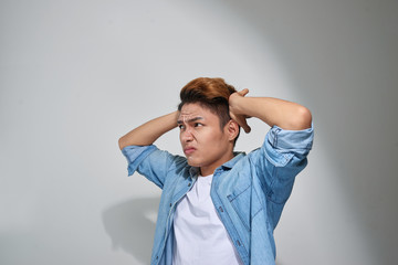 displeased man plugging ears with fingers doesn't want to listen isolated on gray wall background