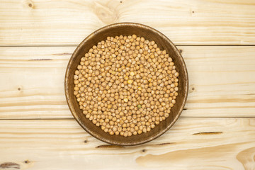 Lot of whole raw chickpeas kabuli variety with wooden bowl flatlay on natural wood