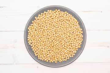 Lot of whole raw chickpeas kabuli variety on grey ceramic plate flatlay on grey wood